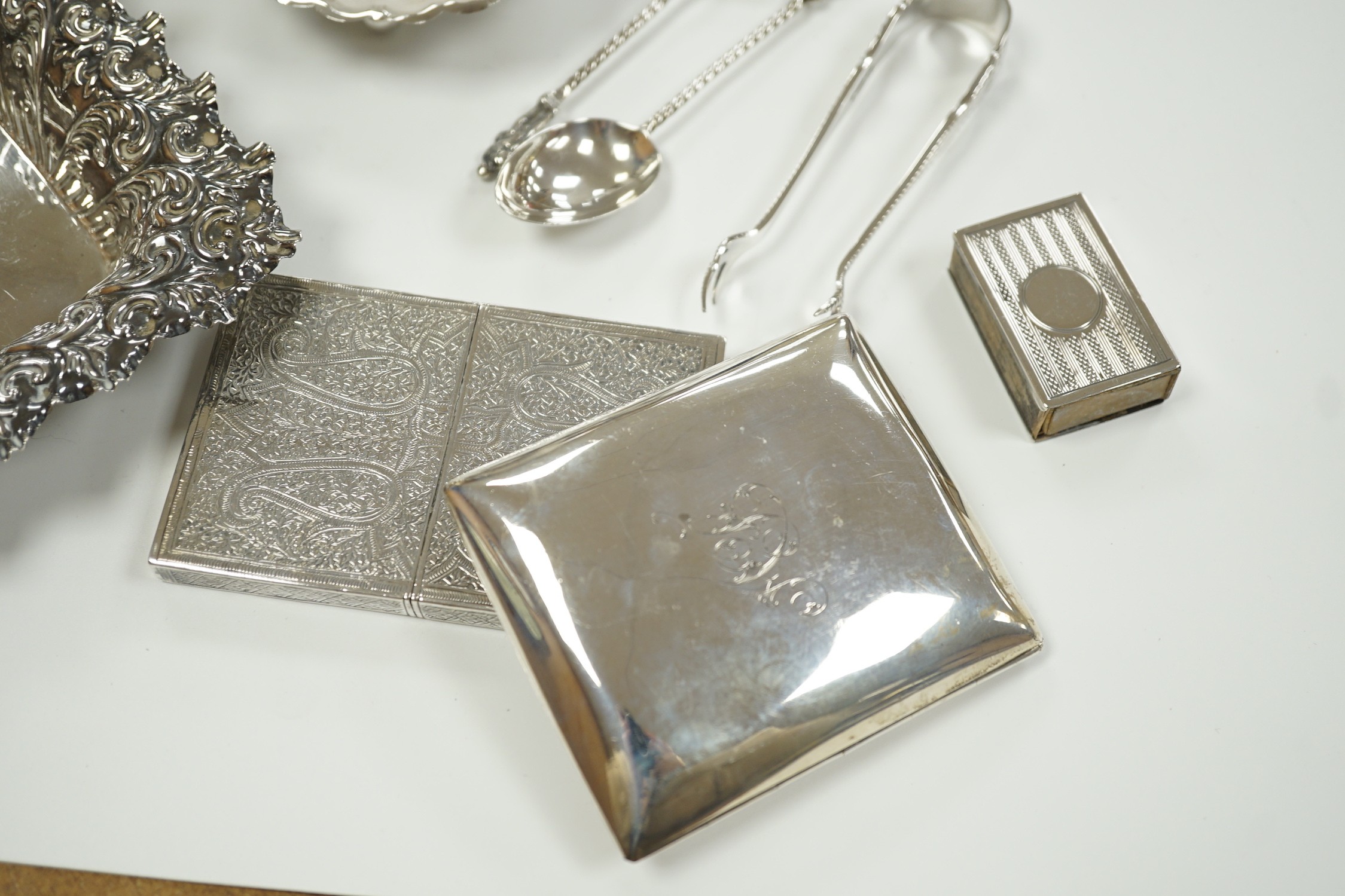 A small group of collectable silver including a repousse bonbon dish, 13.5cm, cigarette case, silver cream jug and sugar bowl, butter shell, vesta case, match sleeve, two apostle teaspoons and a George III curved silver